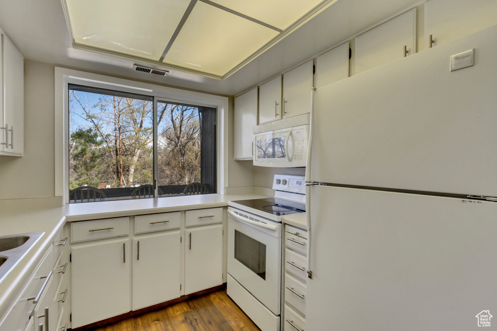 Kitchen with visible vents, dark wood finished floors, white appliances, white cabinets, and light countertops