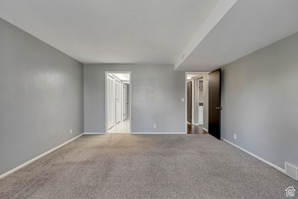 Spare room featuring carpet flooring, visible vents, and baseboards