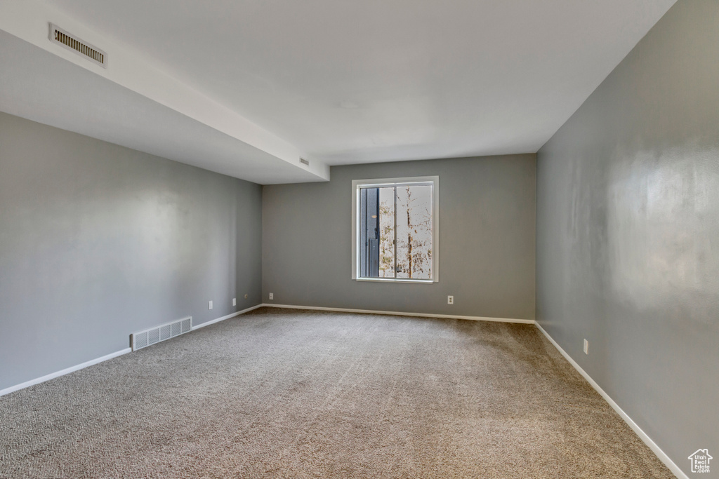 Empty room featuring visible vents, baseboards, and carpet floors