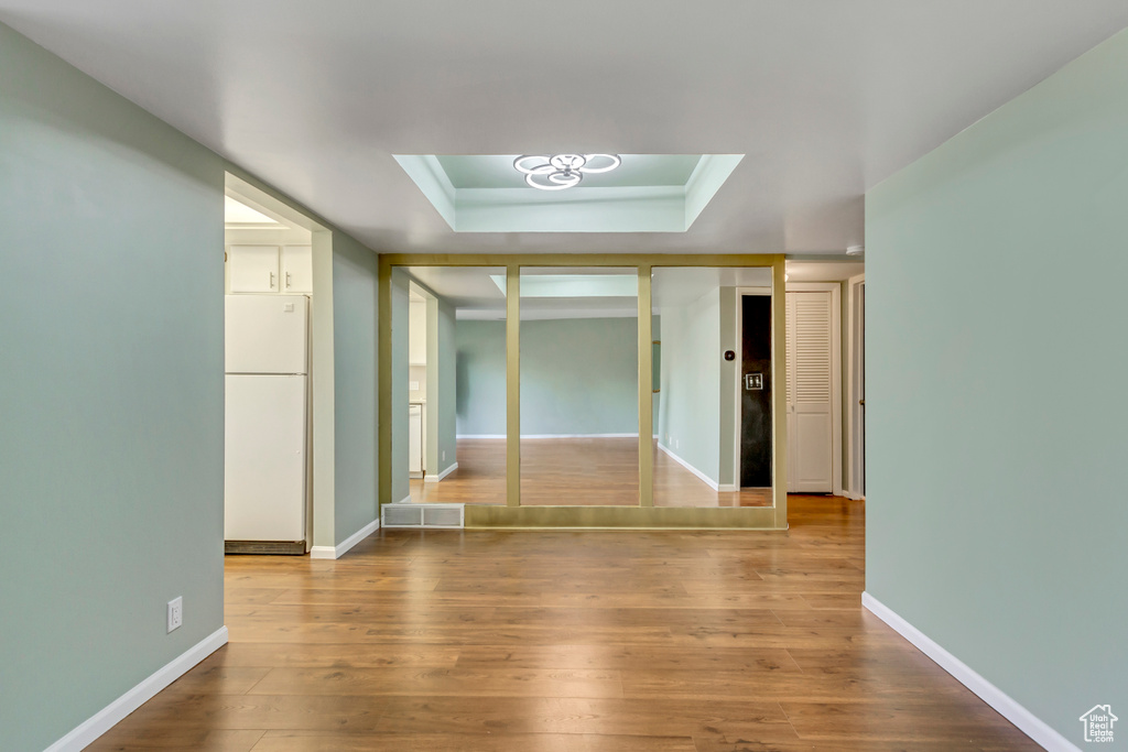 Empty room with a raised ceiling, baseboards, and wood finished floors