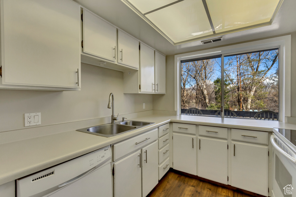 Kitchen featuring visible vents, a sink, dark wood finished floors, white appliances, and light countertops