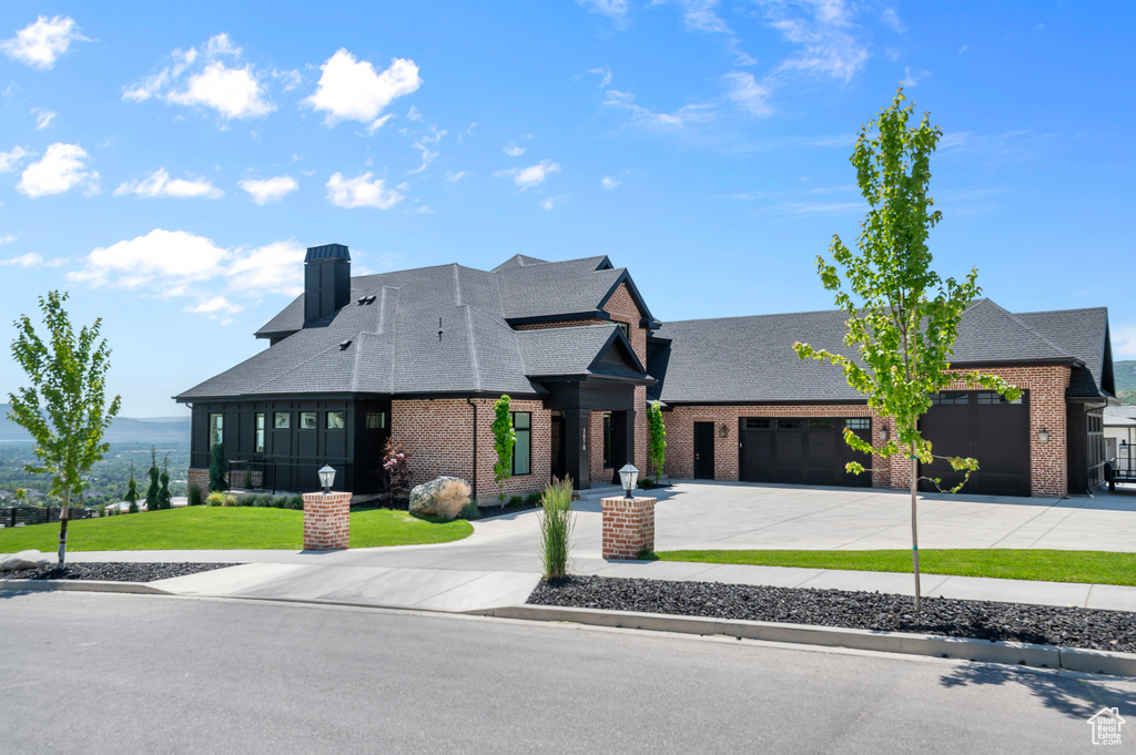 View of front of house with curved driveway, brick siding, and a shingled roof