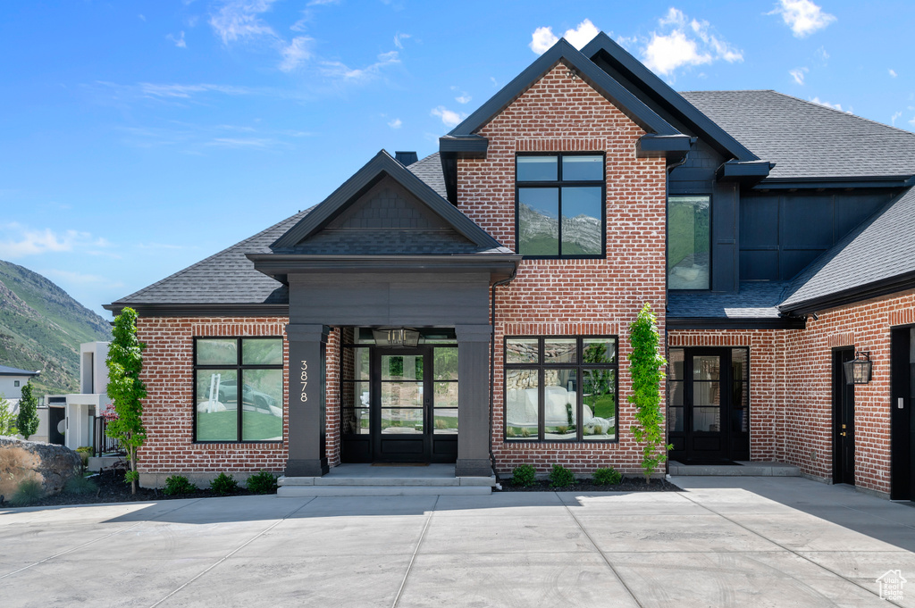 View of front of home featuring brick siding, roof with shingles, and a mountain view