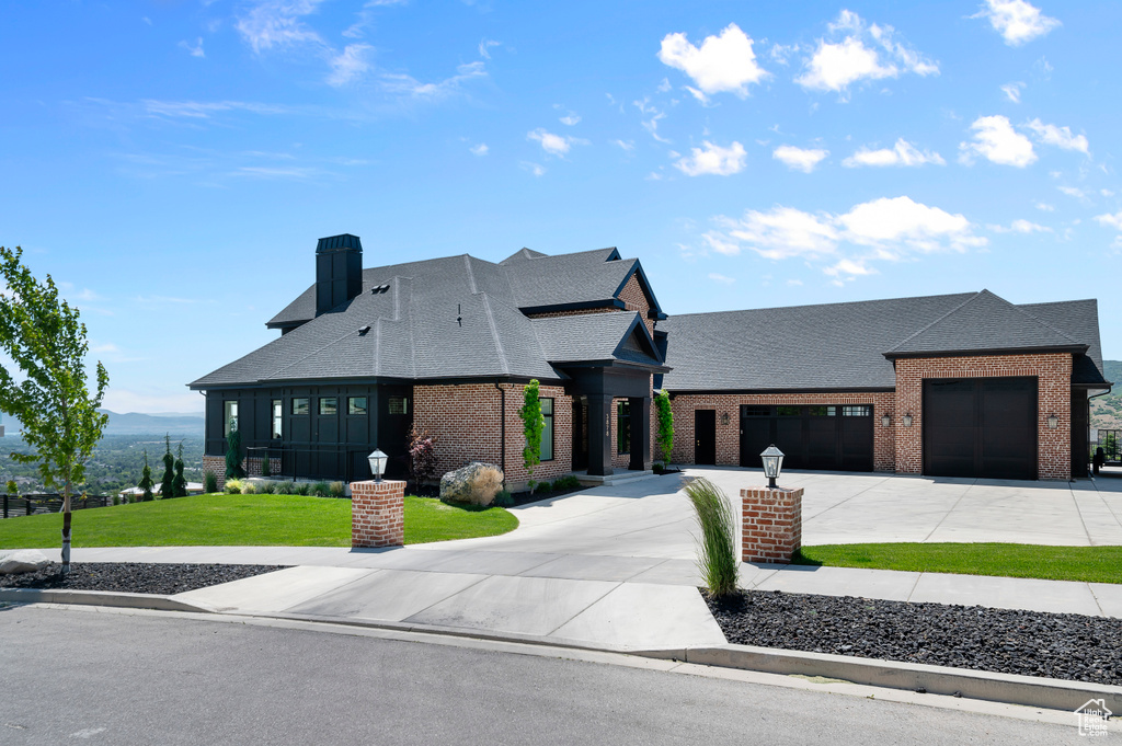 View of front of house with brick siding, roof with shingles, a garage, and concrete driveway
