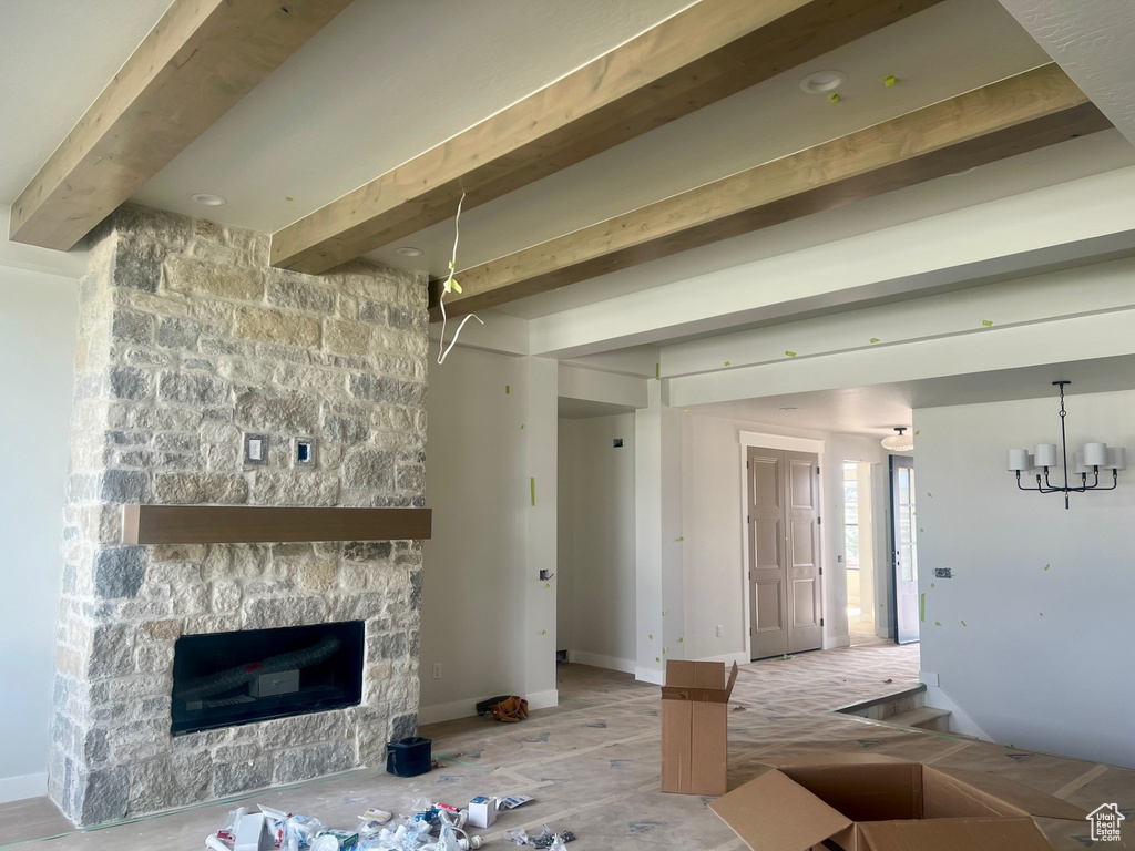 Unfurnished living room featuring beam ceiling, a fireplace, a chandelier, and baseboards