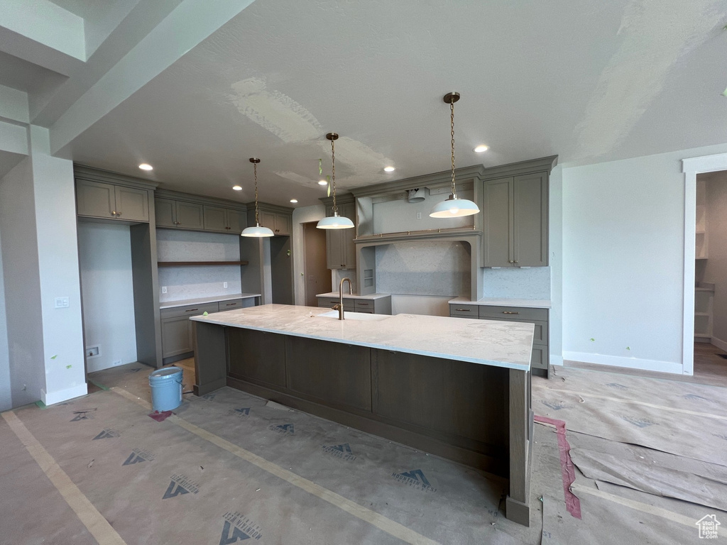 Kitchen featuring gray cabinets, recessed lighting, a large island with sink, and decorative light fixtures