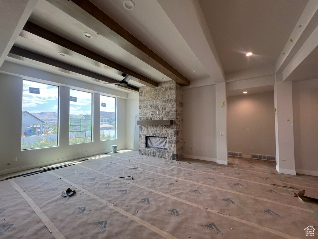 Unfurnished living room featuring beamed ceiling, a stone fireplace, and recessed lighting