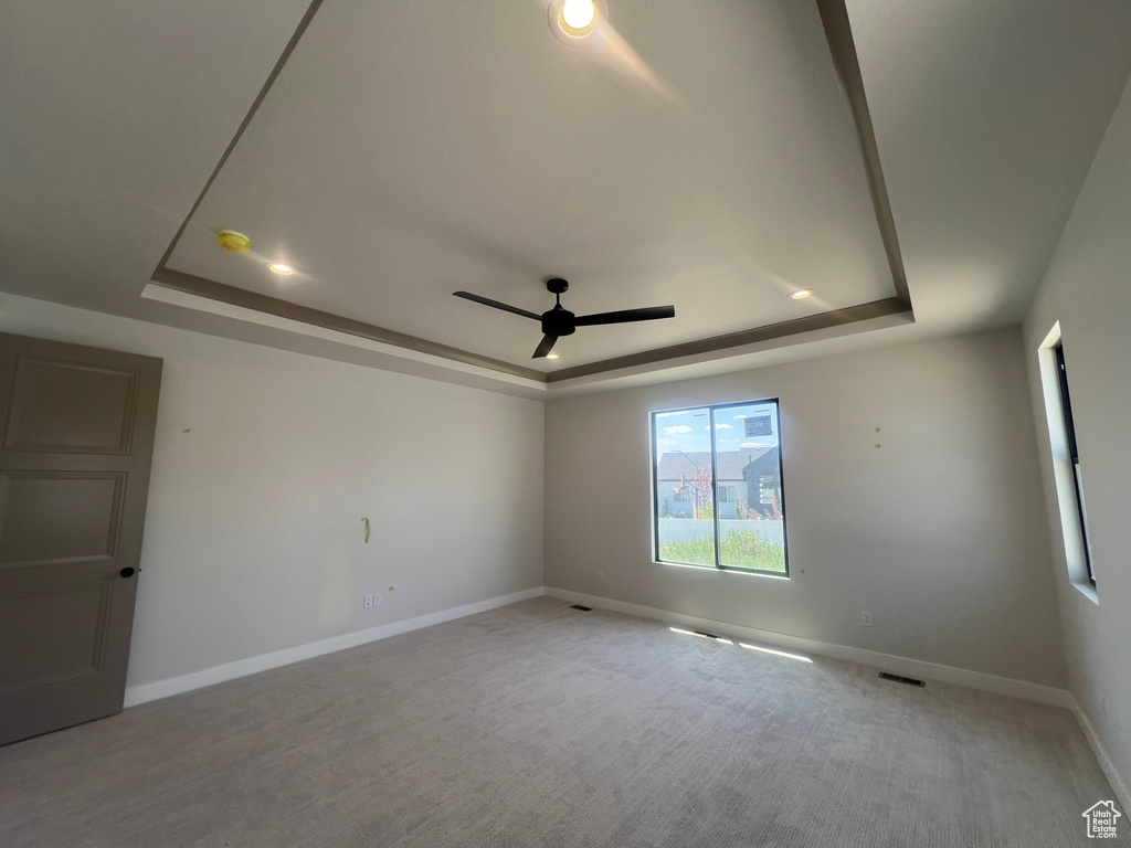 Carpeted empty room featuring a raised ceiling, ceiling fan, and recessed lighting