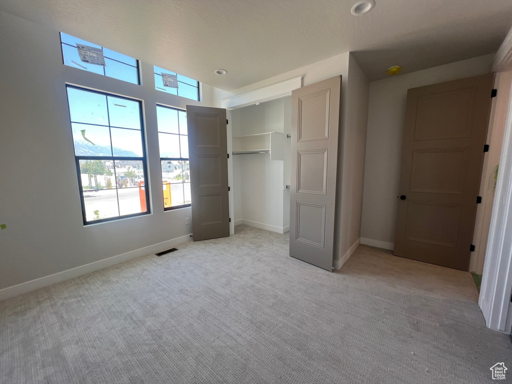 Unfurnished bedroom with light carpet and a closet