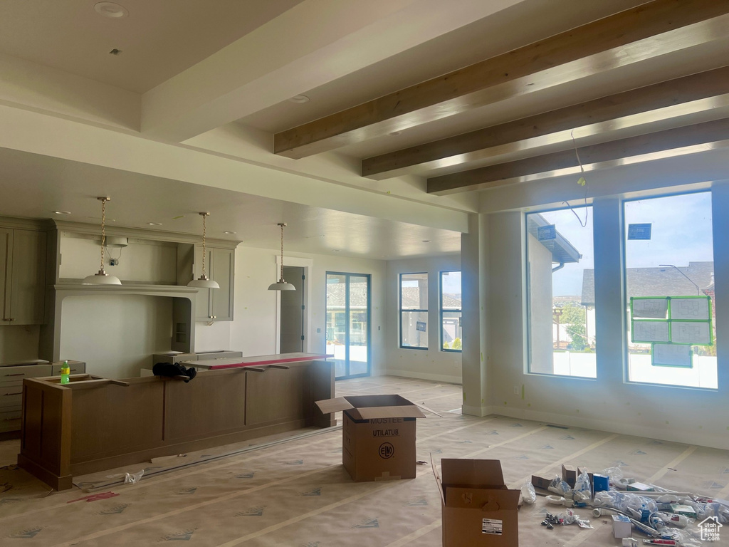 Kitchen featuring hanging light fixtures, beamed ceiling, a kitchen island, and baseboards