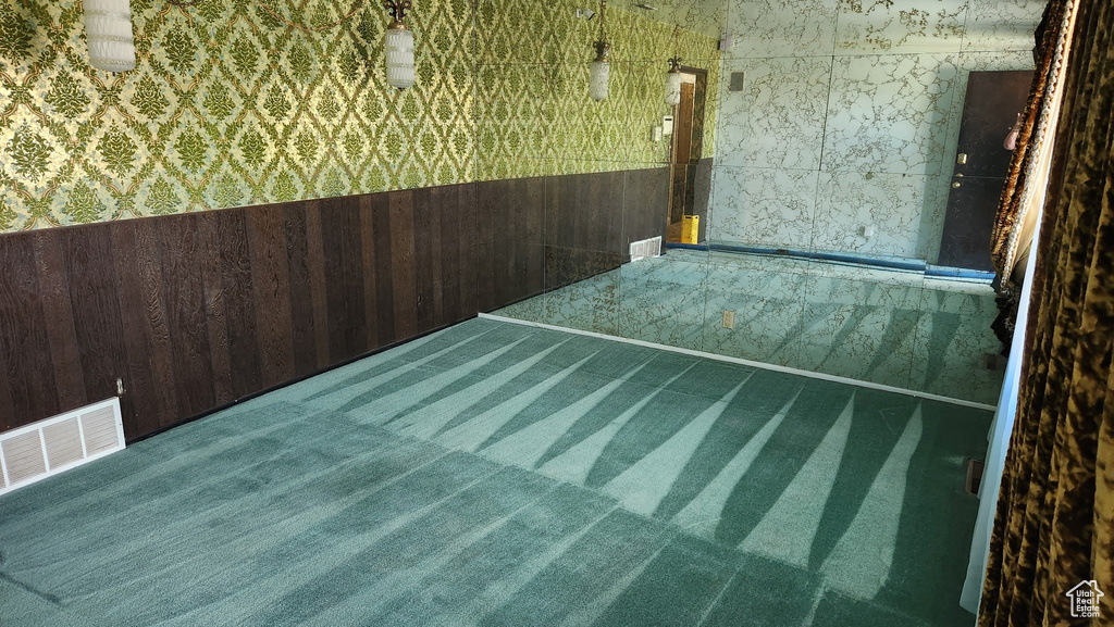 Unfurnished room with carpet flooring, a wainscoted wall, visible vents, and wallpapered walls