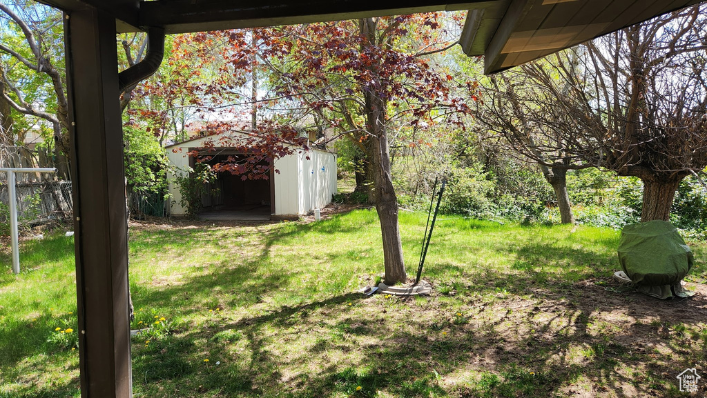 View of yard with fence, an outdoor structure, and a shed
