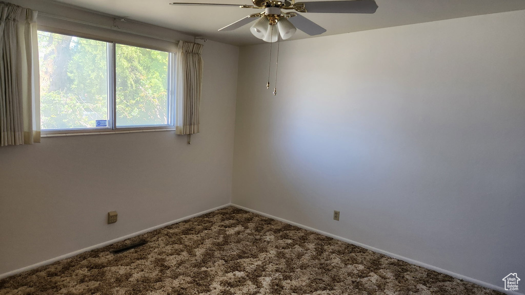 Carpeted empty room featuring baseboards, a ceiling fan, and visible vents