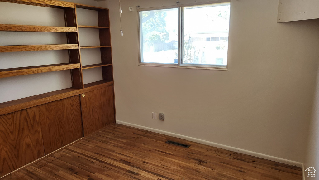 Unfurnished room with dark wood finished floors, visible vents, and baseboards