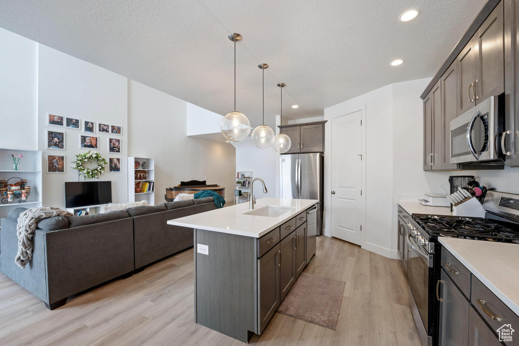 Kitchen featuring a sink, stainless steel appliances, light wood-style floors, and light countertops