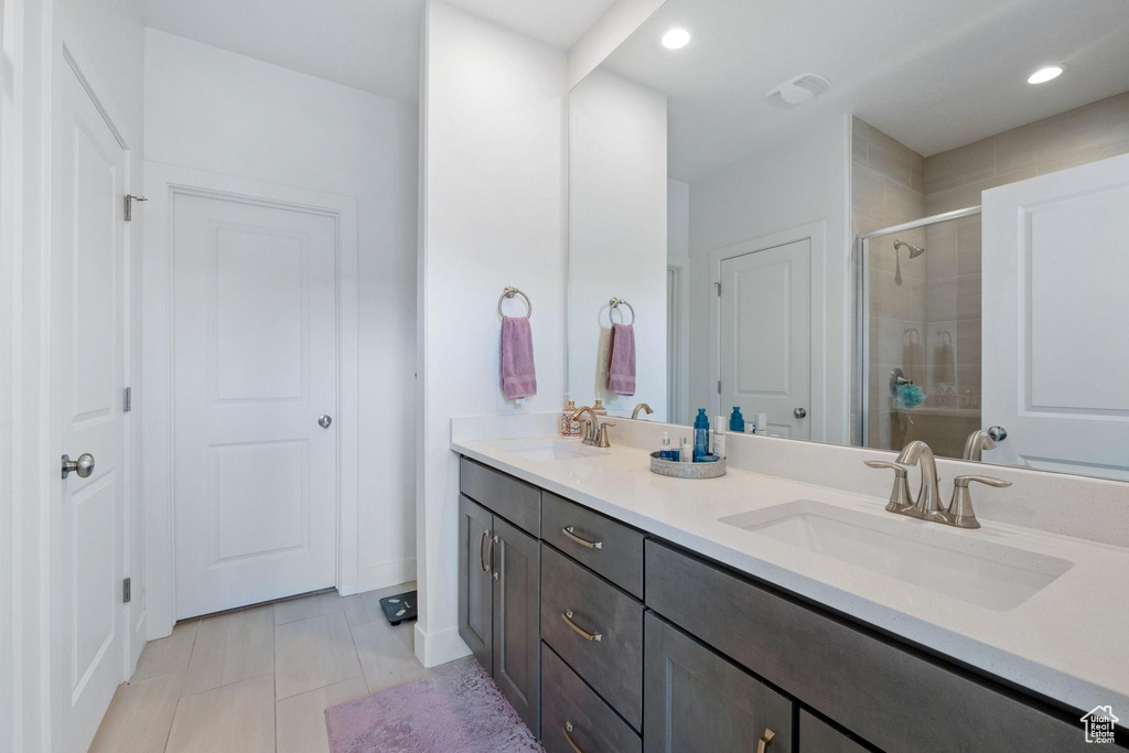 Bathroom with double vanity, recessed lighting, a shower stall, and a sink