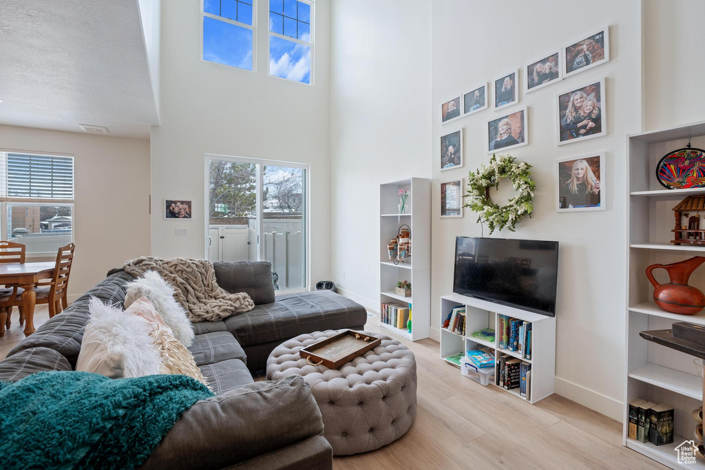Living area with a high ceiling, baseboards, and wood finished floors