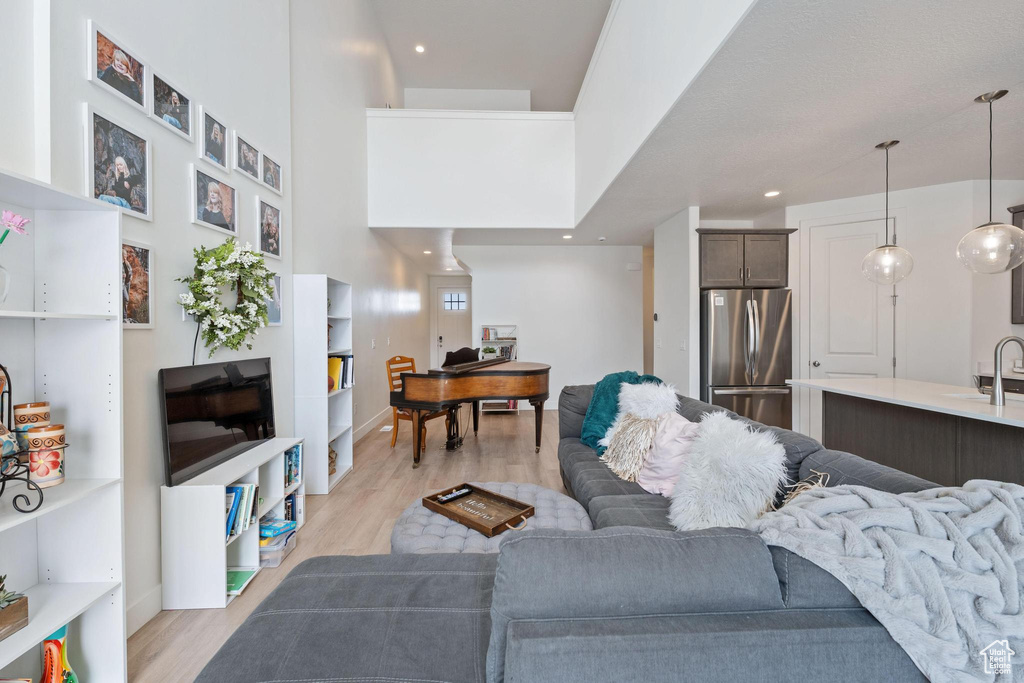 Living area with recessed lighting, baseboards, light wood-style floors, and a high ceiling