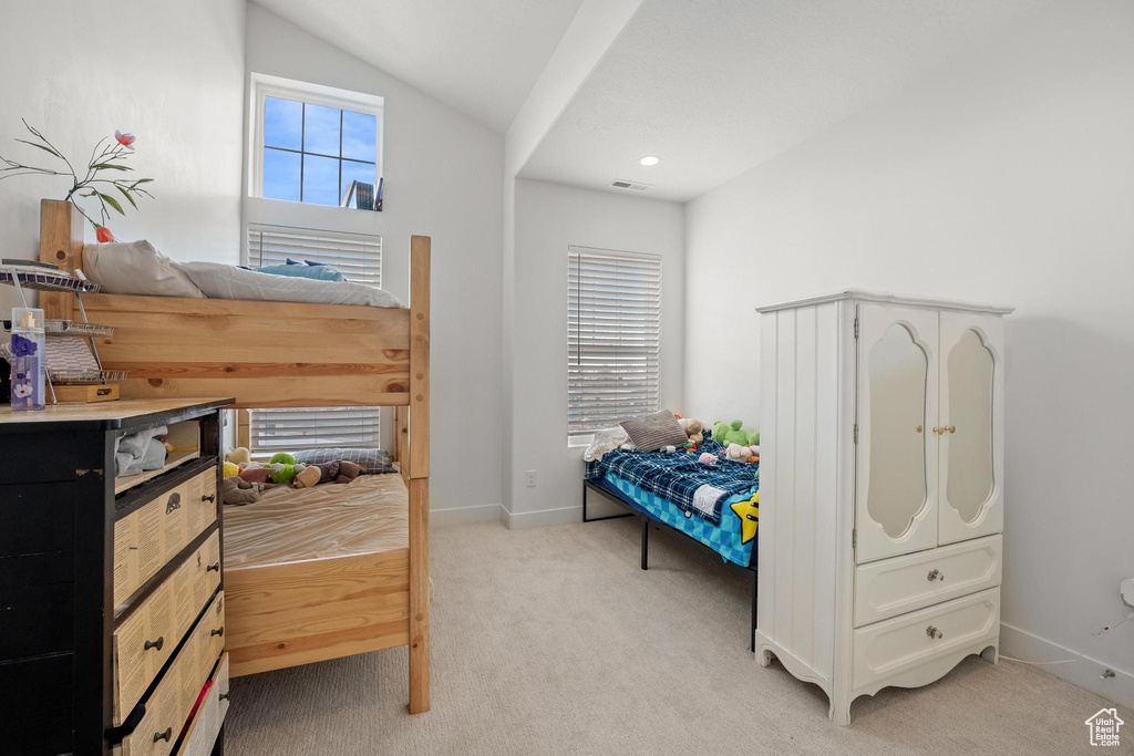 Bedroom with vaulted ceiling, baseboards, visible vents, and light carpet