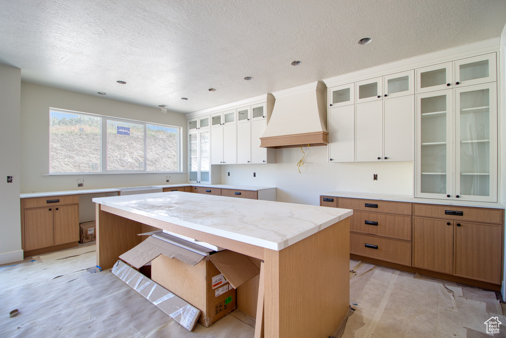 Kitchen with premium range hood, glass insert cabinets, a textured ceiling, recessed lighting, and white cabinetry