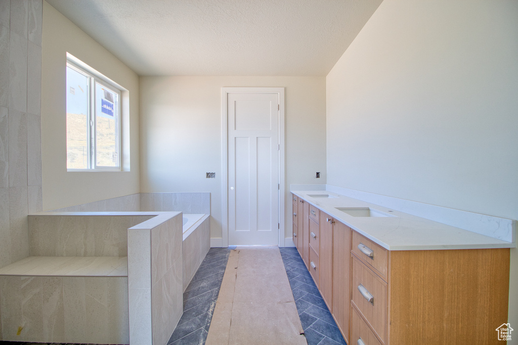 Bathroom featuring a bath, tile patterned flooring, vanity, and a textured ceiling