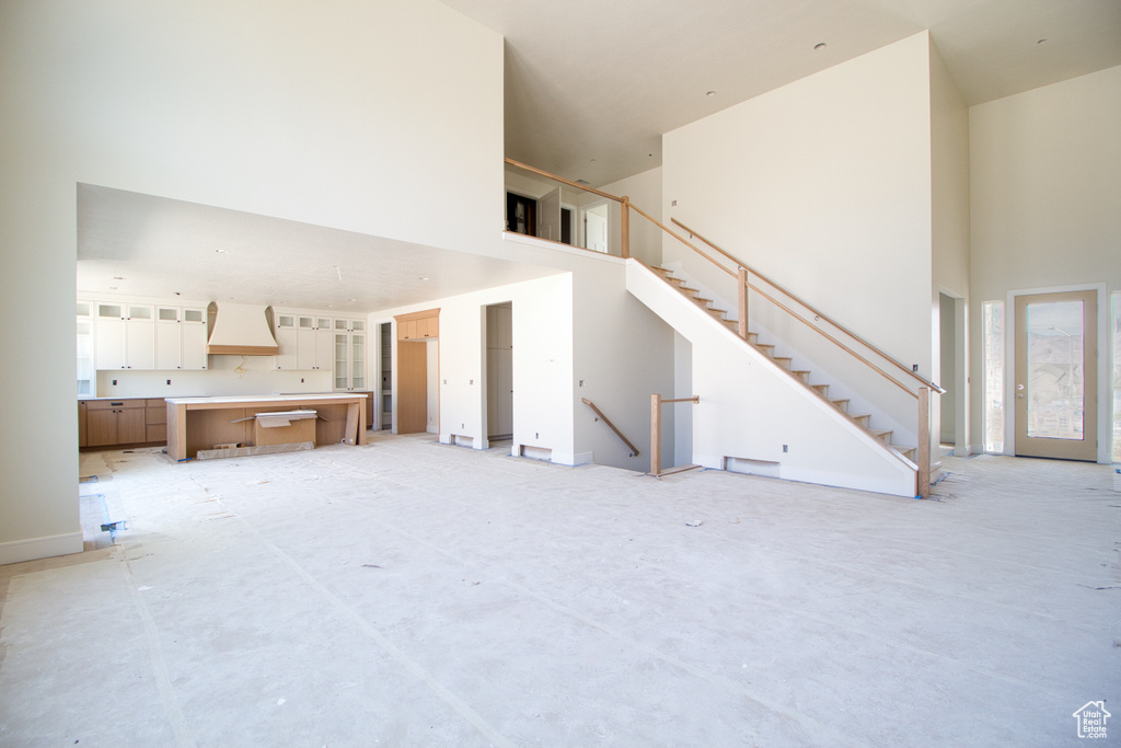Unfurnished living room featuring a towering ceiling and stairs