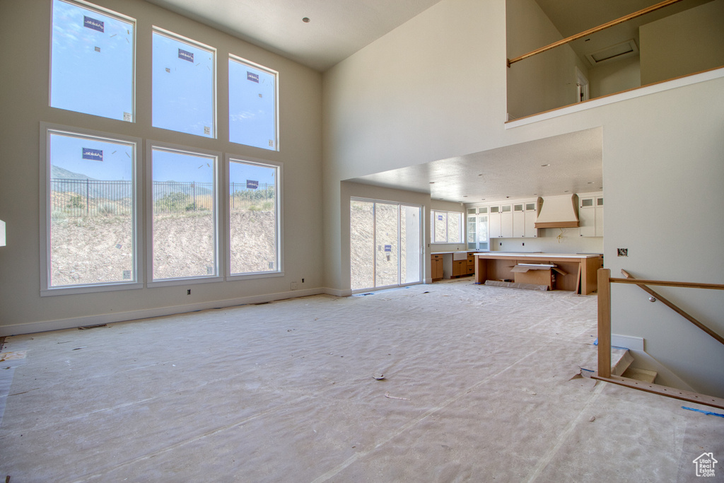 Unfurnished living room with a towering ceiling and baseboards