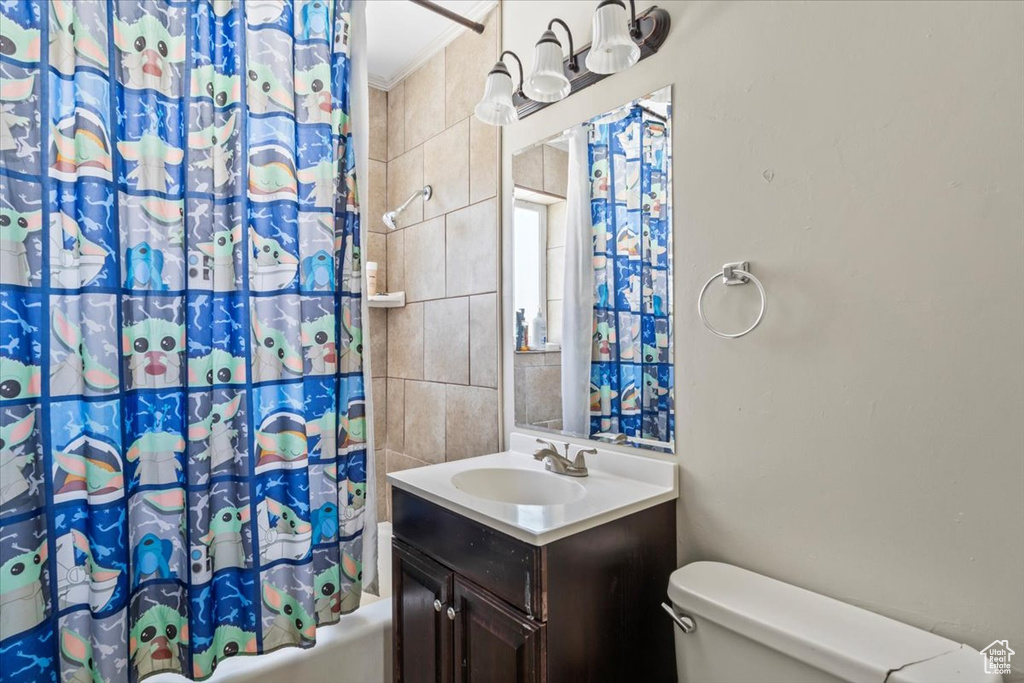 Full bathroom featuring toilet, vanity, ornamental molding, shower / bath combination with curtain, and tile walls