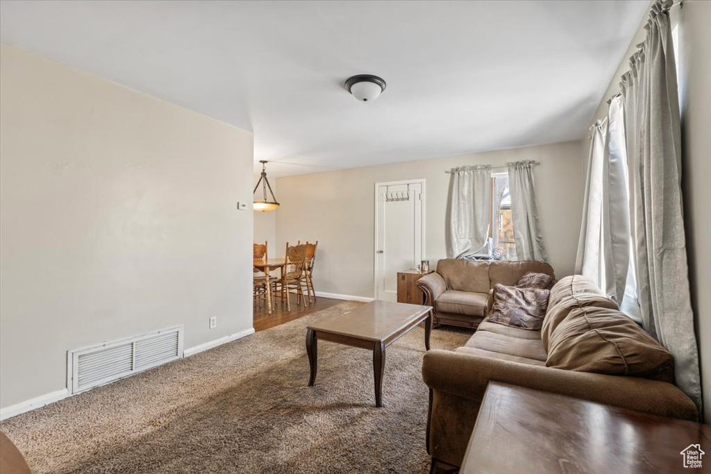 Living area with carpet, visible vents, and baseboards