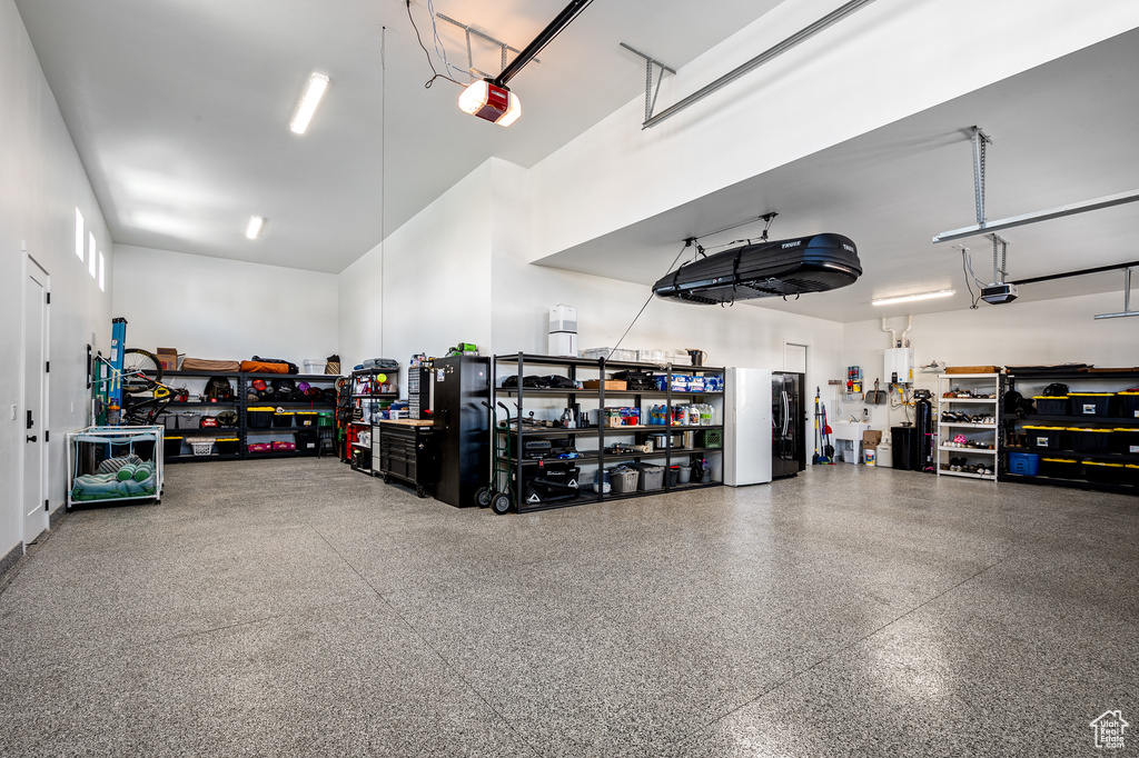 Garage with a workshop area, a garage door opener, and freestanding refrigerator
