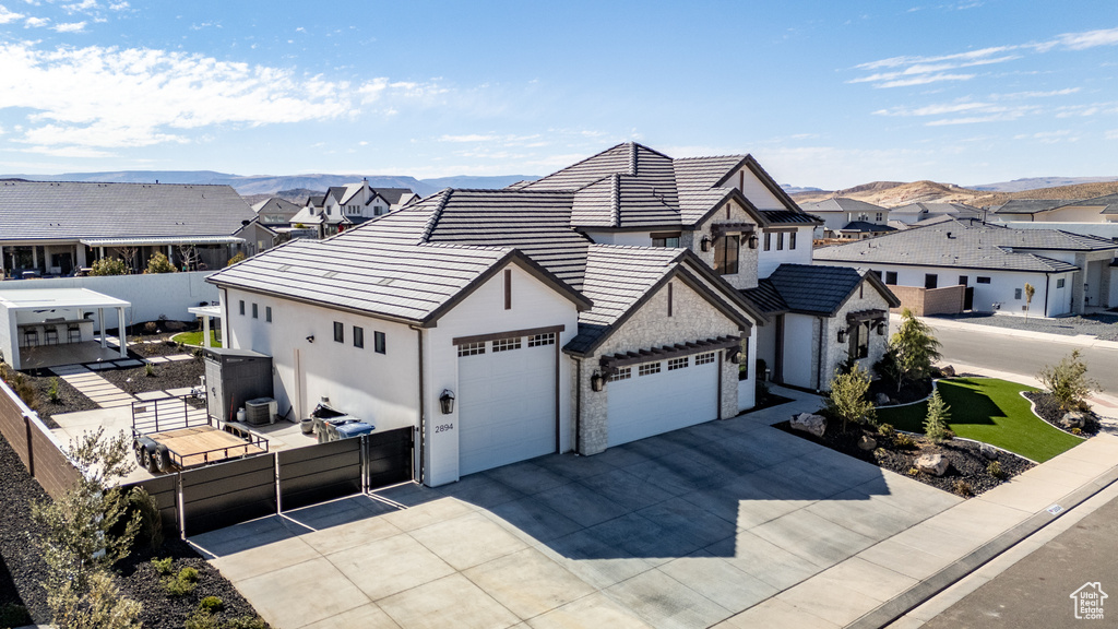 View of front of house with fence, concrete driveway, a garage, a tiled roof, and a residential view