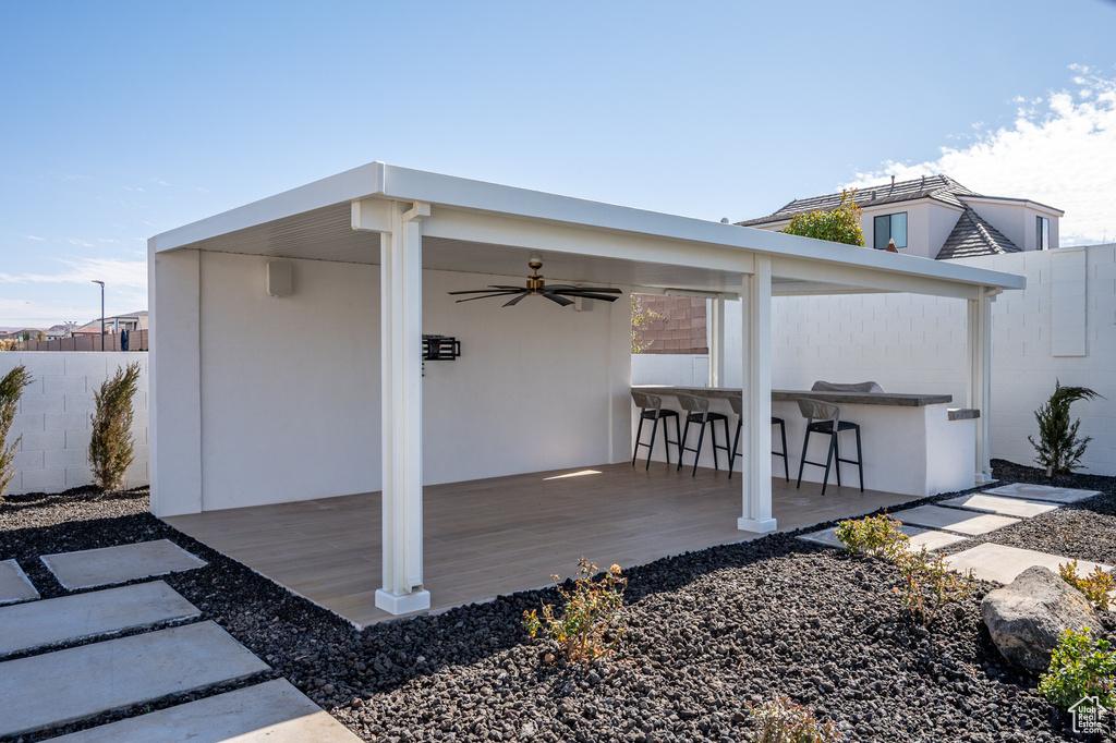Exterior space with outdoor dry bar, ceiling fan, and fence