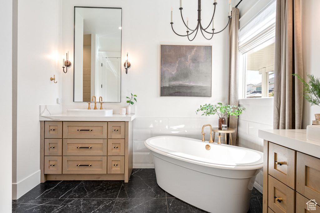 Full bath featuring marble finish floor, a freestanding bath, and vanity