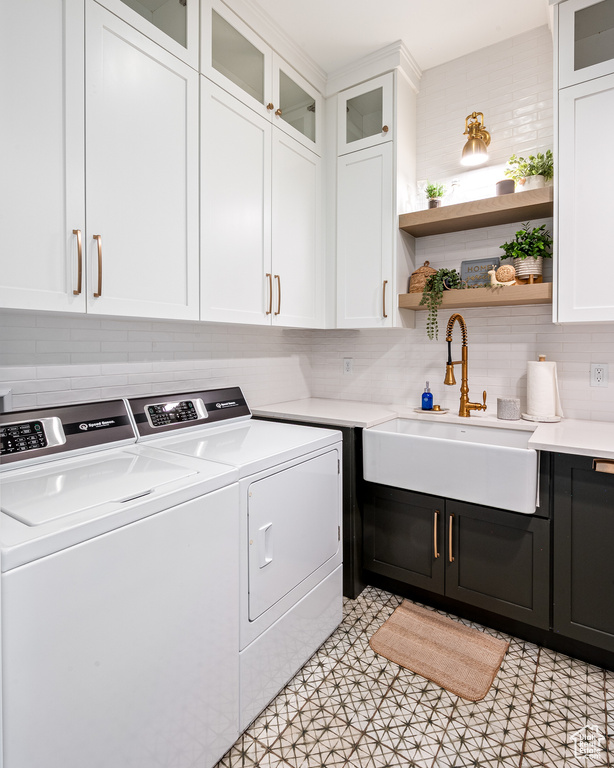 Laundry area with separate washer and dryer, cabinet space, and a sink