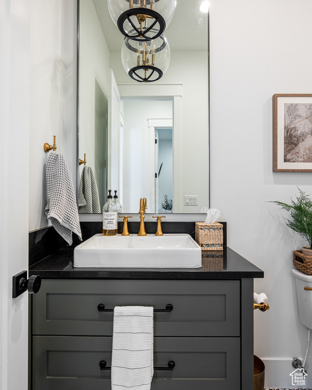 Bathroom featuring toilet, a chandelier, and vanity