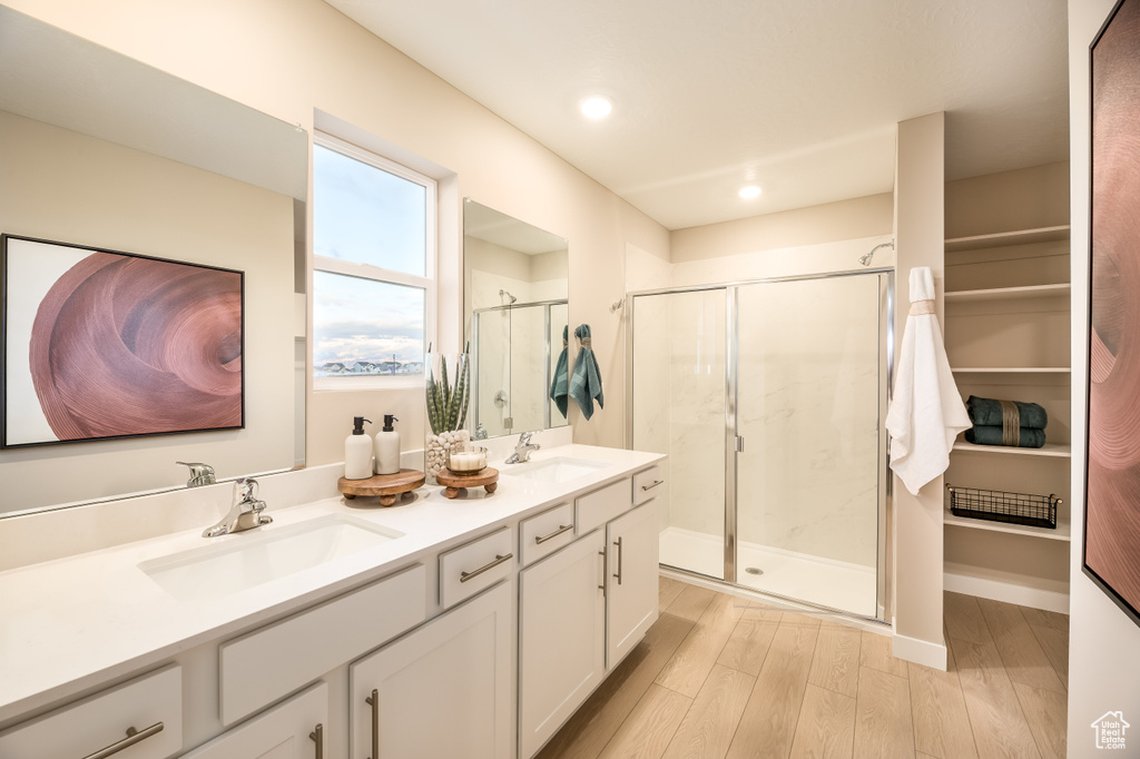 Full bath featuring a sink, double vanity, wood finished floors, and a shower stall