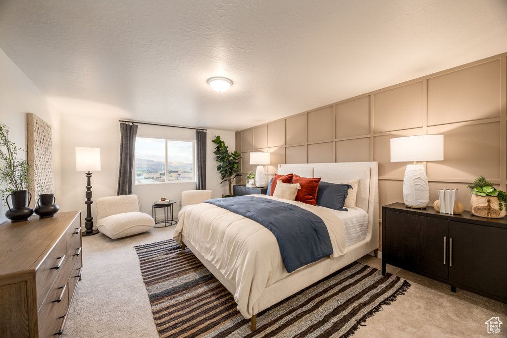 Bedroom featuring a decorative wall, light colored carpet, and a textured ceiling