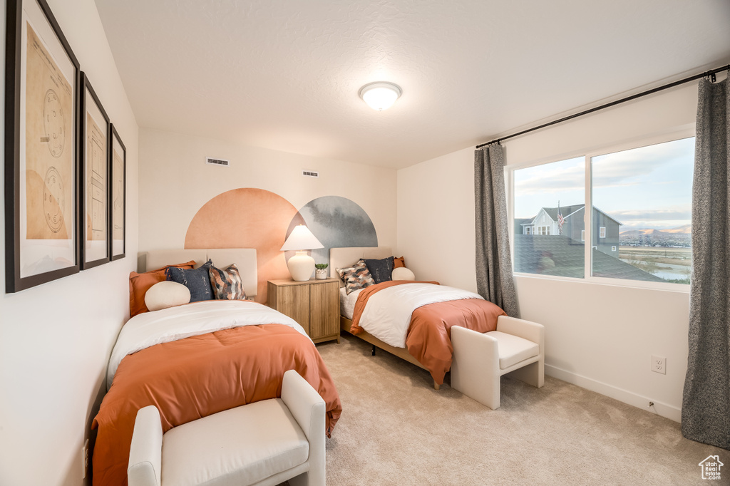 Bedroom featuring visible vents, light carpet, and baseboards