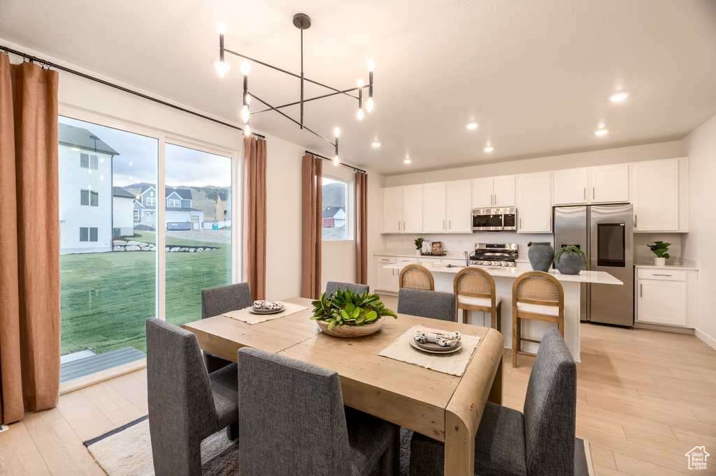 Dining space with recessed lighting, a notable chandelier, and light wood-style flooring