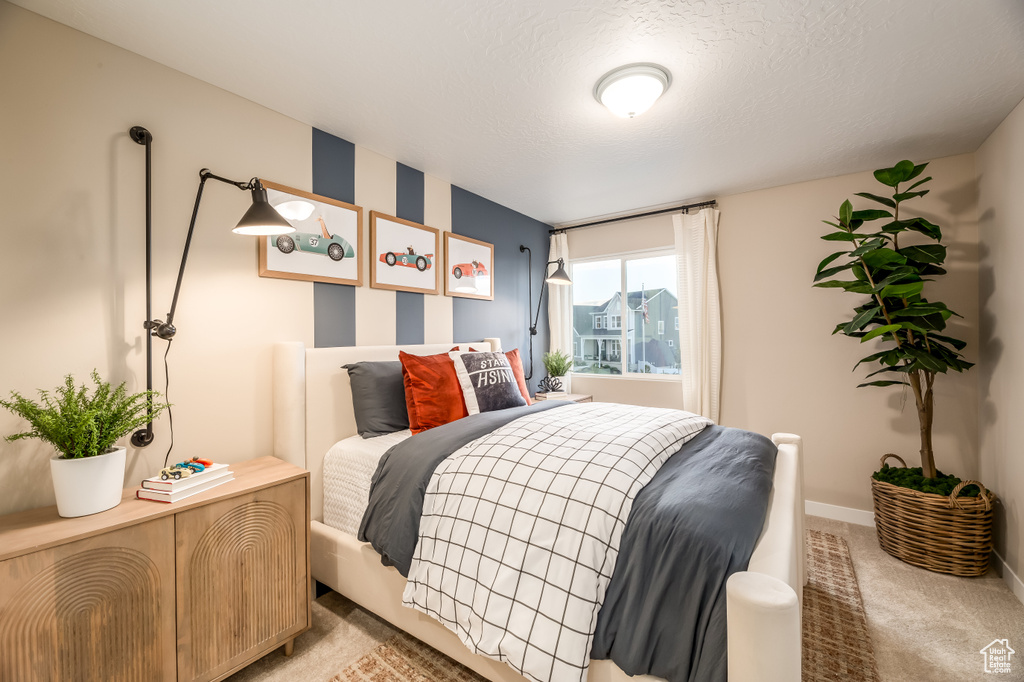 Bedroom featuring a textured ceiling, baseboards, and light carpet