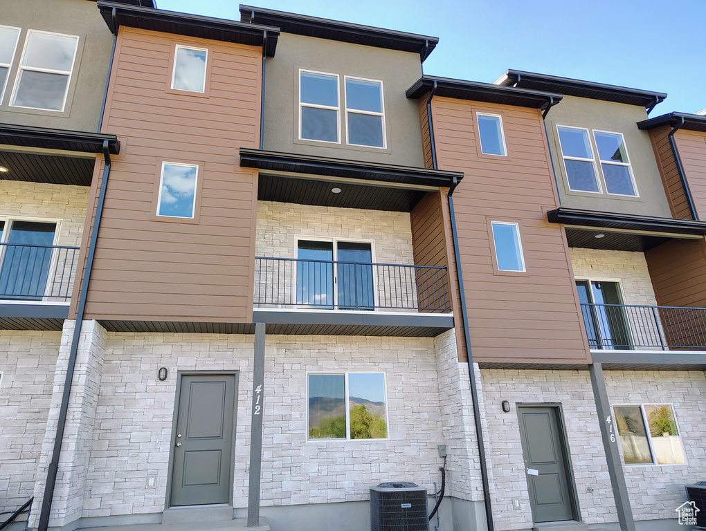 Rear view of property featuring stone siding and cooling unit