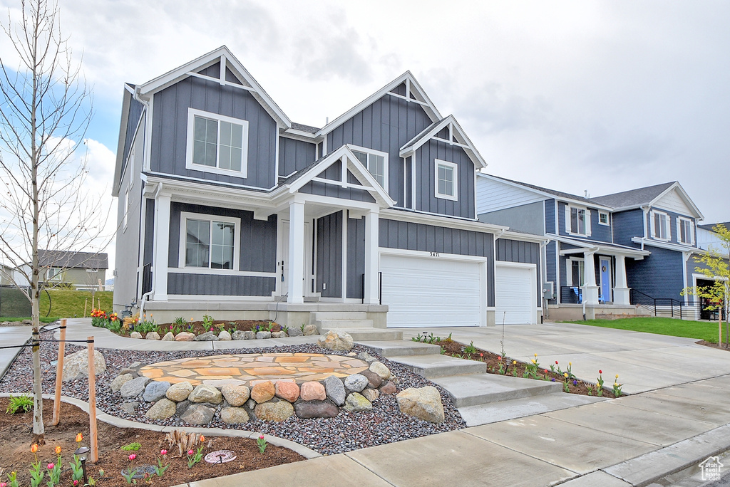 View of front facade with a porch, driveway, a garage, and board and batten siding