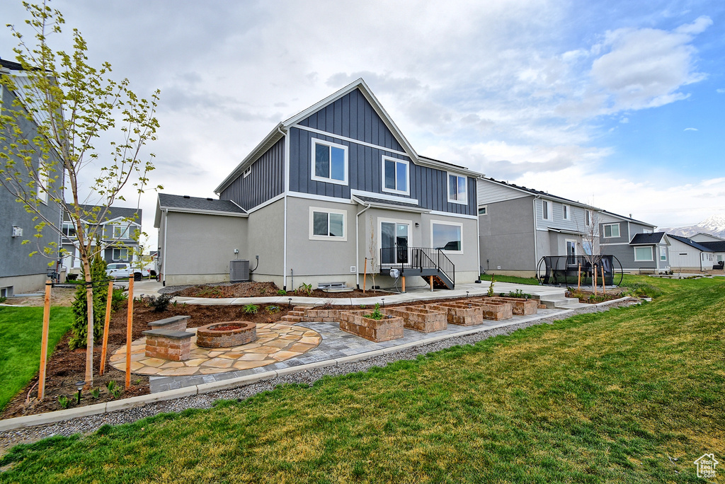 Back of property with a fire pit, board and batten siding, a patio, a residential view, and a yard