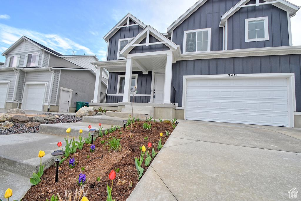 View of front of home with covered porch, board and batten siding, driveway, and a garage