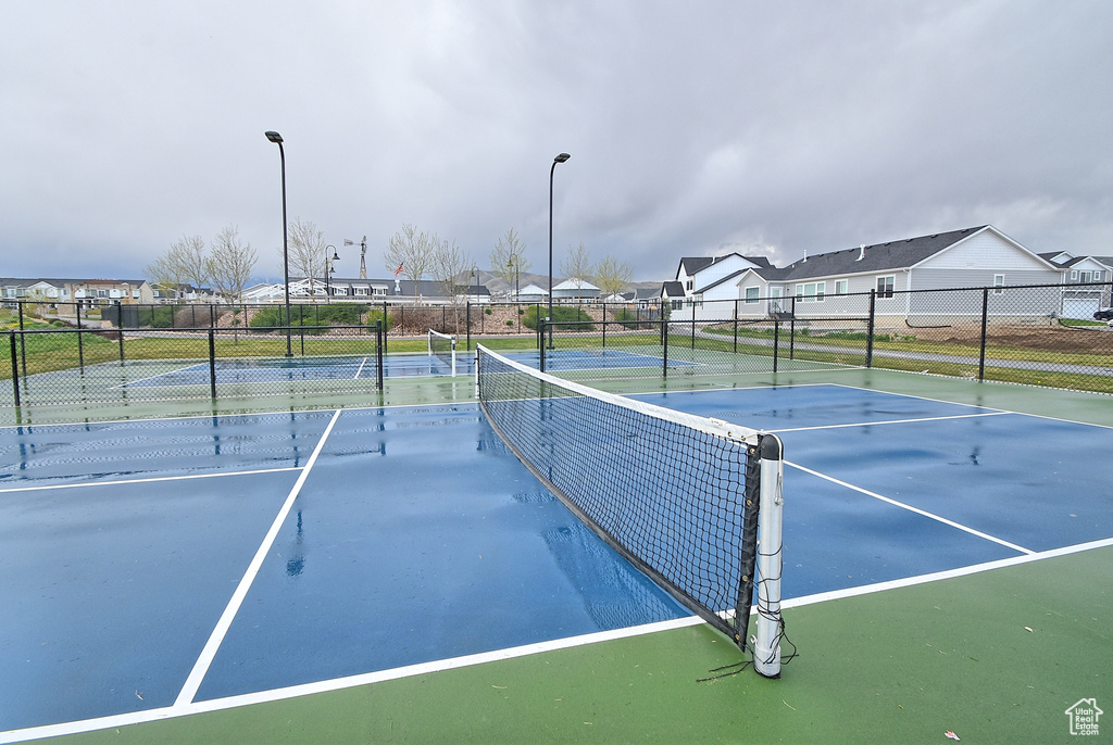 View of tennis court with fence and a residential view