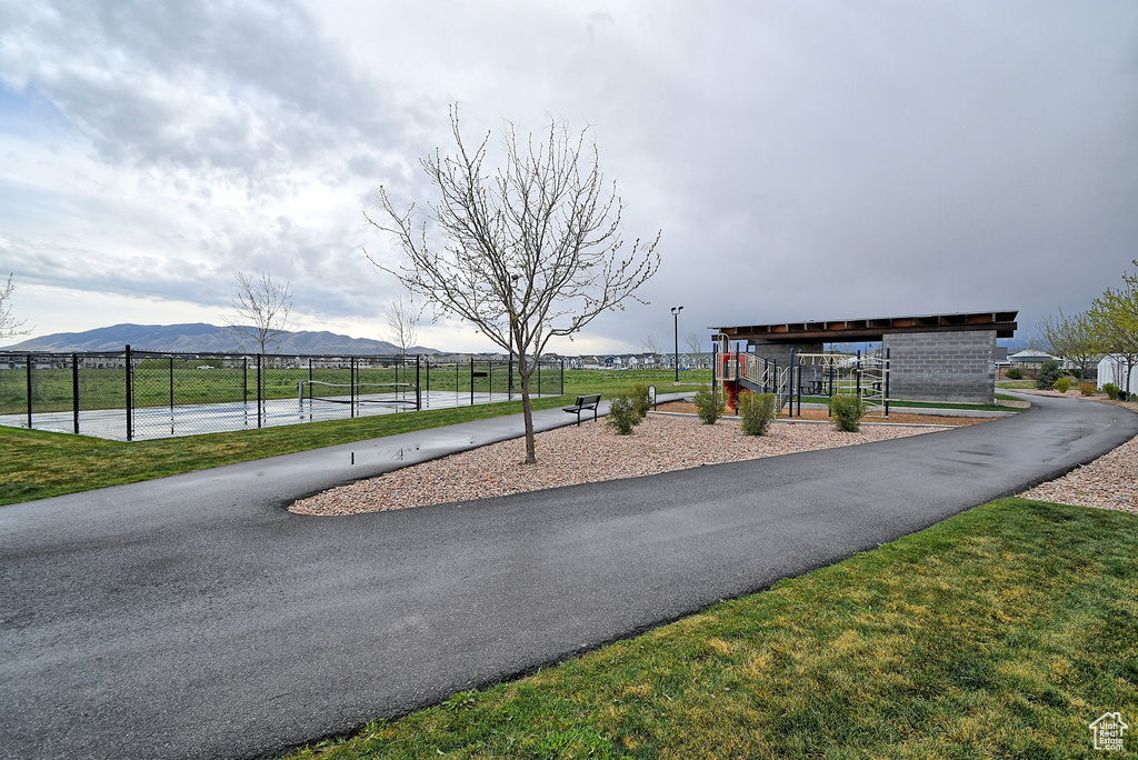 View of play area with a mountain view, a tennis court, and fence