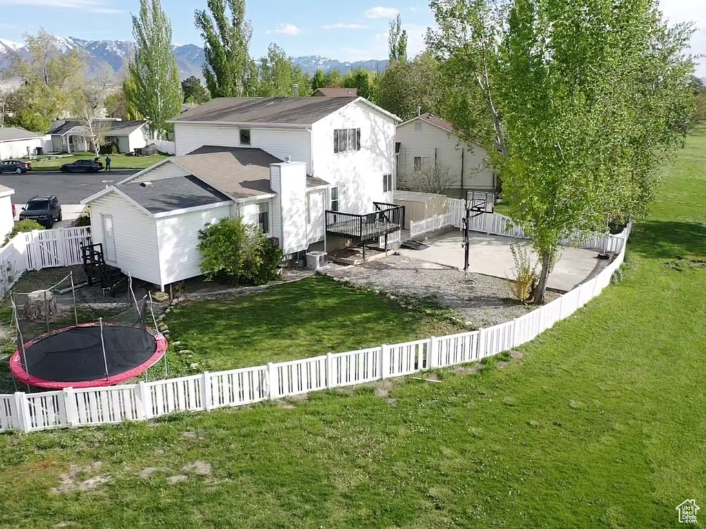 View of yard featuring a mountain view, a residential view, a fenced backyard, and a trampoline