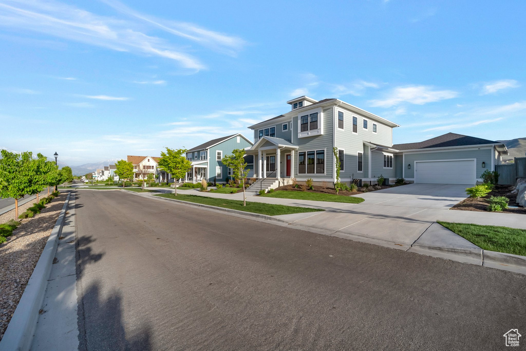View of front of property featuring concrete driveway, an attached garage, and a residential view