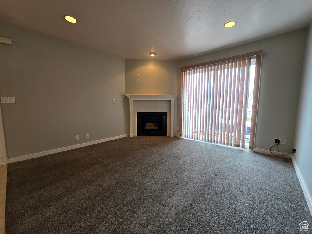 Unfurnished living room with recessed lighting, baseboards, carpet, and a tiled fireplace