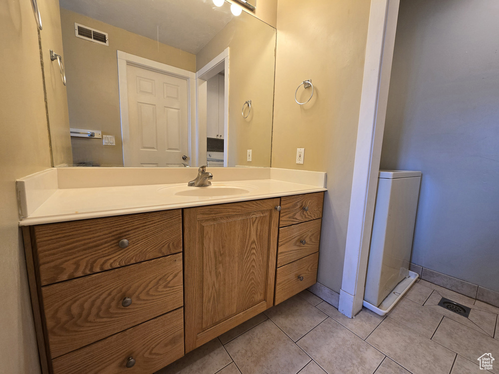 Bathroom with visible vents, baseboards, vanity, and tile patterned flooring